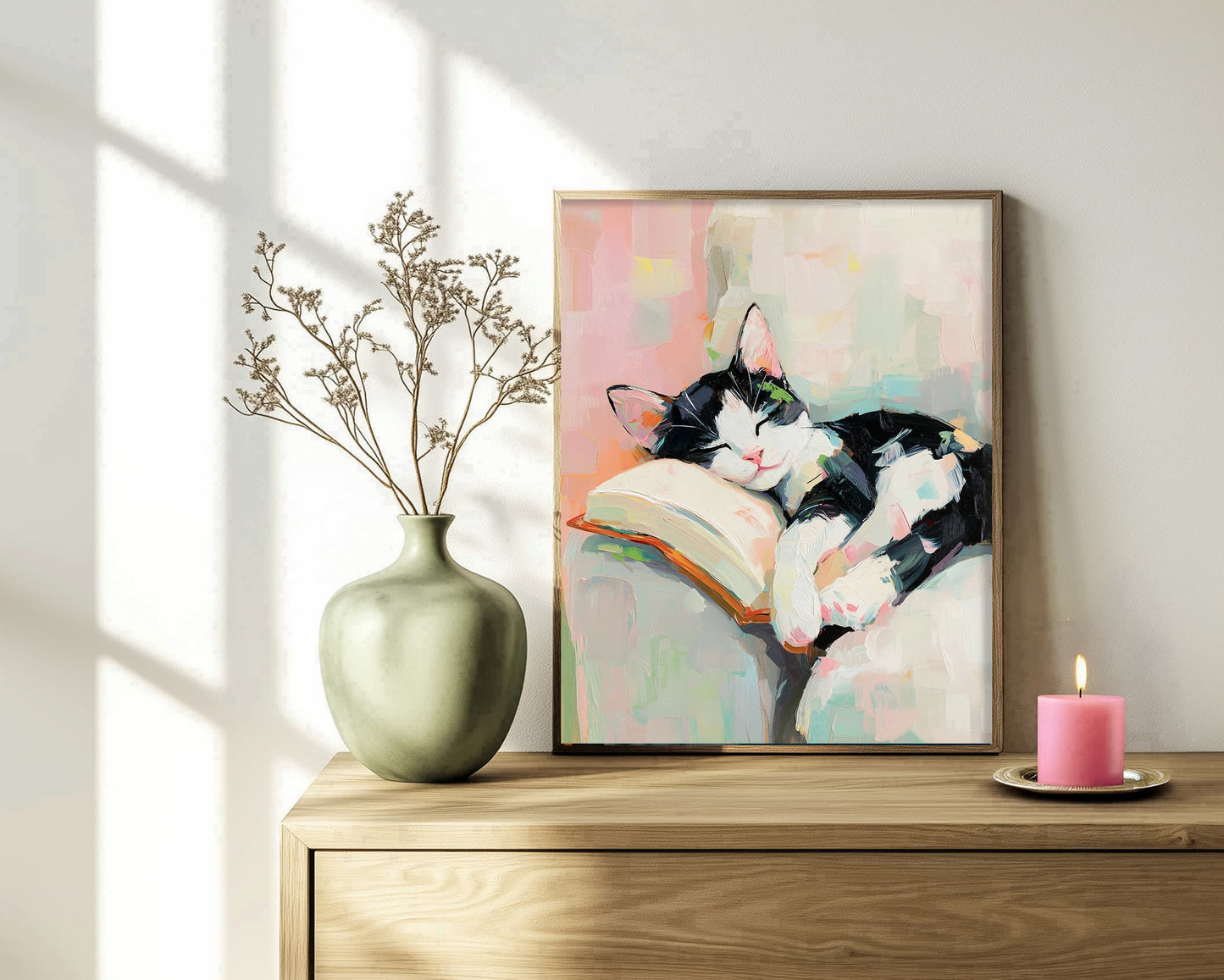 Framed painting of a cat reading a book on a wooden surface with a vase and candle.